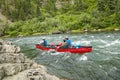 Men canoeing on rough river rapids in wild Alaska