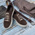 Men casual outfit. Men`s shoes, clothing and accessories on wooden background - jeans, shirt, sneakers, belt. Top view. Flat lay Royalty Free Stock Photo