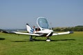 Men check the small personal airplane before taking off and prepare for the flight next to grass landing strip