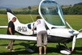 Men check the small personal airplane before taking off and prepare for the flight next to grass landing strip