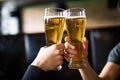 Men cheers with beer in glasses in pub. Close up. Royalty Free Stock Photo