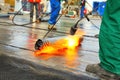 Men crout roof with hot tar