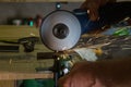 Men cuts a small metal sheet with an electric grinder