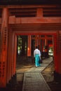 Men dress like Shinto priests, wearing white shirts and green pants. Rear view, walking on a walkway Royalty Free Stock Photo