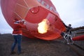 Men dressed as Santa Claus preparing hot-air balloon for launching, gas burner flaming. Royalty Free Stock Photo