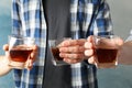 Men drink, cheers. Glasses of whiskey against background, close up