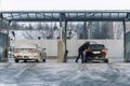 Men driver at car wash with high pressure water equipment pump at self-service outdoor cold snow frosty winter day Royalty Free Stock Photo