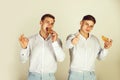 Men eating buns on grey background Royalty Free Stock Photo