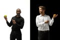 Men eating a hamburger and fruits on a black and white background Royalty Free Stock Photo