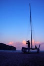 Men enjoying photography with camera near a sailboat on the beach in the evening