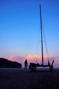 Men enjoying photography with camera near a sailboat on the beach in the evening