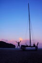 Men enjoying photography with camera near a sailboat on the beach in the evening