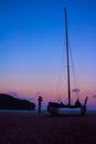 Men enjoying photography with camera near a sailboat on the beach in the evening