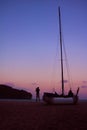 Men enjoying photography with camera near a sailboat on the beach in the evening