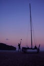 Men enjoying photography with camera near a sailboat on the beach in the evening