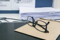 Men eyeglasses on office desk with envelope and tons of business documents piles Royalty Free Stock Photo