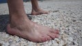 Men feet stand on broken shells on the beach