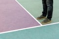 Men feet stand on the rubberized sports playground painted in pastel colors