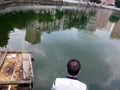 The men are fishing near the pond