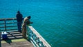 Men fishing on a pier at the coast Royalty Free Stock Photo