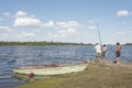 Men fishing with rods next to a rowboat on the bank of the Rio Negro, Uruguay