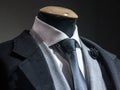 Men formal Suit, with a white shirt, a black tie, and a black lapel flower pin and grey jacket on display on dummy in front Royalty Free Stock Photo