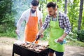 Men friends cooking meat on barbecue grill at outdoor summer party Royalty Free Stock Photo