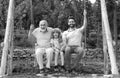 Men generation family playing on swing together Three different generations ages: grandfather father and son swinging Royalty Free Stock Photo