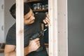 Men in gray clothes work as a screwdriver, fixing a wooden frame for the window to the gypsum plasterboard partition. Royalty Free Stock Photo