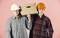 Men with grumpy faces hold cardboard box on pink background. Delivery, warehouse and packaging concept. Siblings with