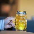 Men Hand with glass mug of golden Freshly filled beer. Real scene in bar, pub. Beer culture, Craft brewery, uniqueness Royalty Free Stock Photo