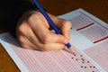 Hand with pencil filling out answers on exam test answer sheet Royalty Free Stock Photo