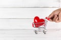 Men Hand Push Trolley Shopping Cart with Red Heart over white wood background. Love Concept with Copy Space