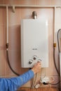Men hand regulate the temperature of hot water in Gas water heater.