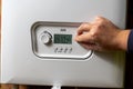 Men hand setting temperature button on control panel of central heating at combi boiler. Incressing price for gas Royalty Free Stock Photo