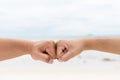 Men hands fist bumping together on blurred sea and sky