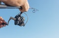 Men hands holding flying fishing rod or angler over blue clear sky Royalty Free Stock Photo