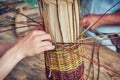 Men hands weave craft basket of tree branches. Vintage work of artisans basket-makers in the old days