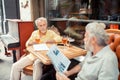 Grey-haired retired men having conversation sitting outside