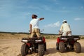 Men in helmets ride on atv in desert, back view Royalty Free Stock Photo