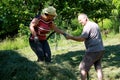 A men helping a woman to step on the ground. Putting the grass on the trailor. Farm chores, working on a field.