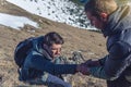 Man helps his friend to climb to the top. Hiker gives a hand to pull up the on mountain.