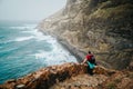 Men hiker with backpack on the scenic coastal road. The route leads along huge volcanic rock cliffs above roaring ocean Royalty Free Stock Photo