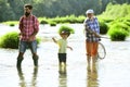 Men hobby. Summer day. Male multi generation family. Family fishermen fishing with spinning reel. Father teaching son Royalty Free Stock Photo