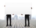 Men holding board standing on wooden floor Royalty Free Stock Photo