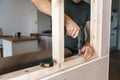 Men in home clothes work with a screwdriver, fixing a wooden frame for a window in their house. Repair yourself Royalty Free Stock Photo