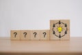 Man icon, bright lightbulb and question marks on wooden cube block for brainstorming, teamwork to solving problem, corporation