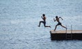 Men jumping in sea off pier