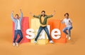 Men Jumping And Shouting Near Big Shopping Bags, Orange Background Royalty Free Stock Photo