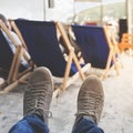 Men legs in sneakers on background of deckchairs on beach Royalty Free Stock Photo